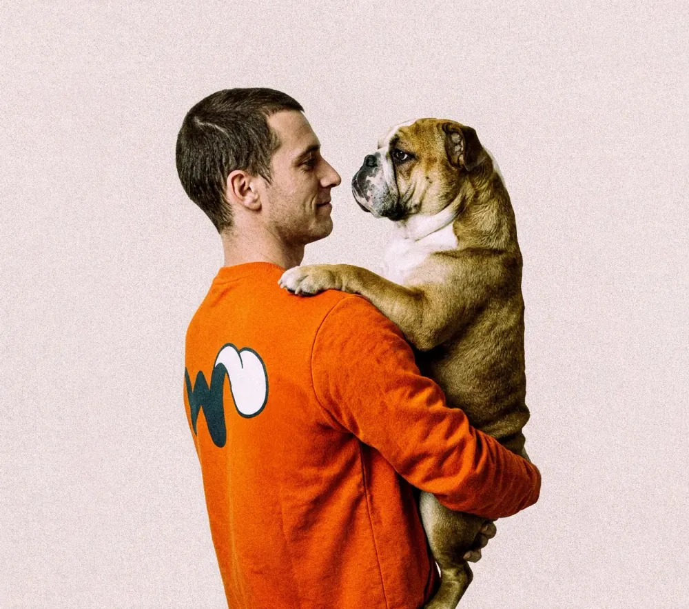 Cuidador con buzo naranja de Wana alzando a un bulldog inglés